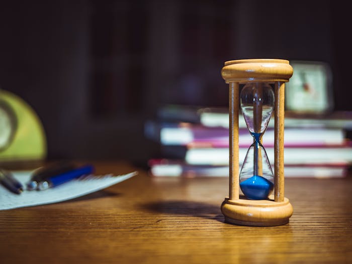 hourglass with blue sand signifying elapsing time before daily late fee hits