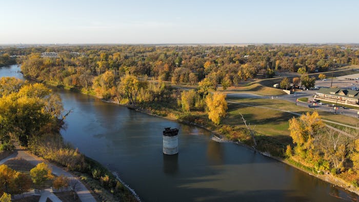 River in Grand Forks, North Dakota running alongside trees with a bridge in the background